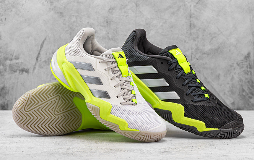 mens and womens adidas barricade 13 tennis shoes sitting on tennis court with tennis ball