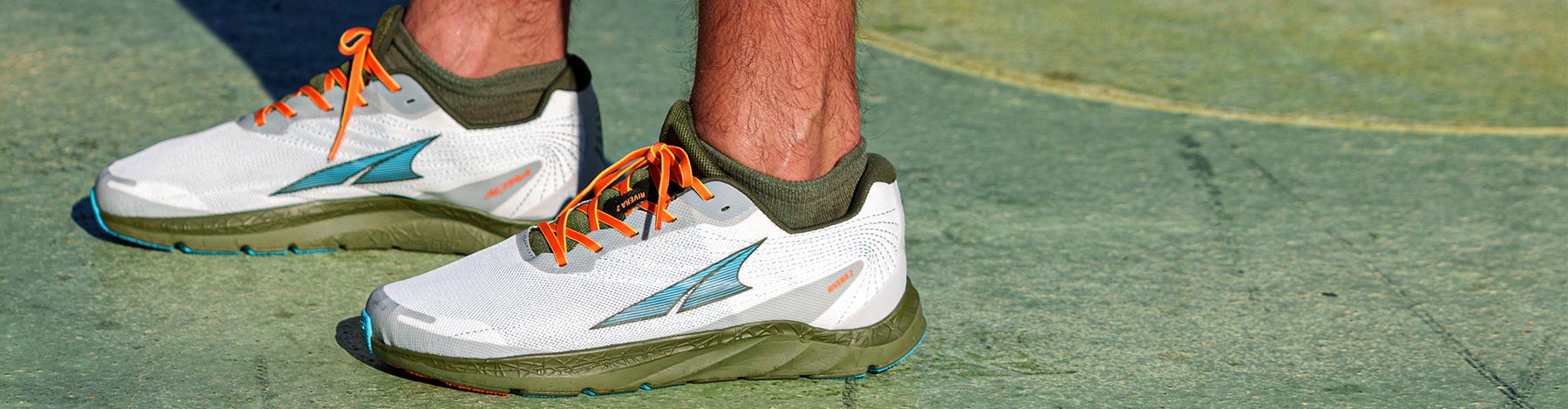 Man standing on a green surface in White/Green Altra Rivera 2 running shoes.