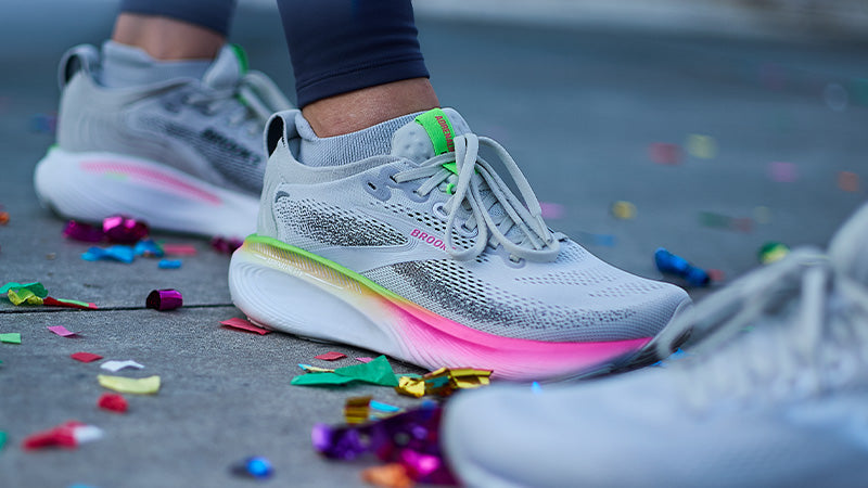 A person wearing Brooks Adrenaline GTS 25 running shoes on a confetti-covered street.