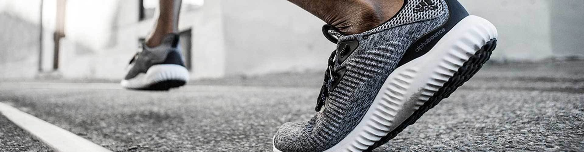 Man running in gray, black, and white adidas running shoes