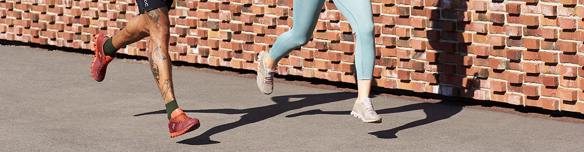 Man and woman running in On Running apparel in nature