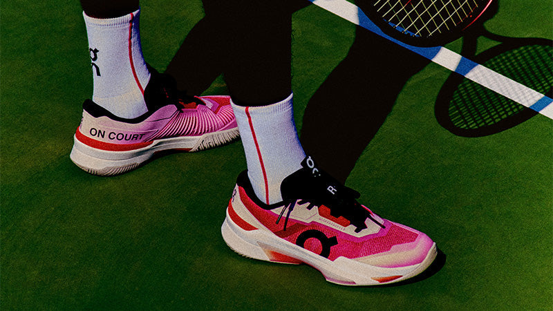 Person wearing pink and black On The Roger Pro Fire tennis shoes on a tennis court