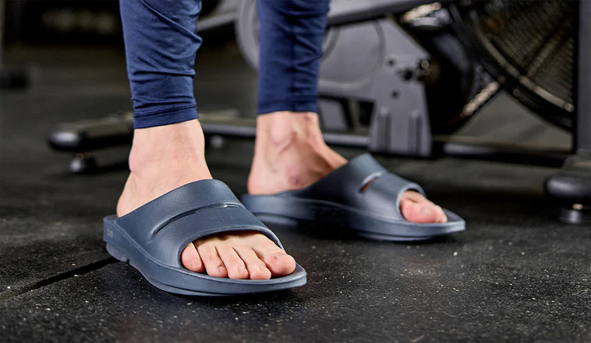 man wearing oofos ooah slides in gym