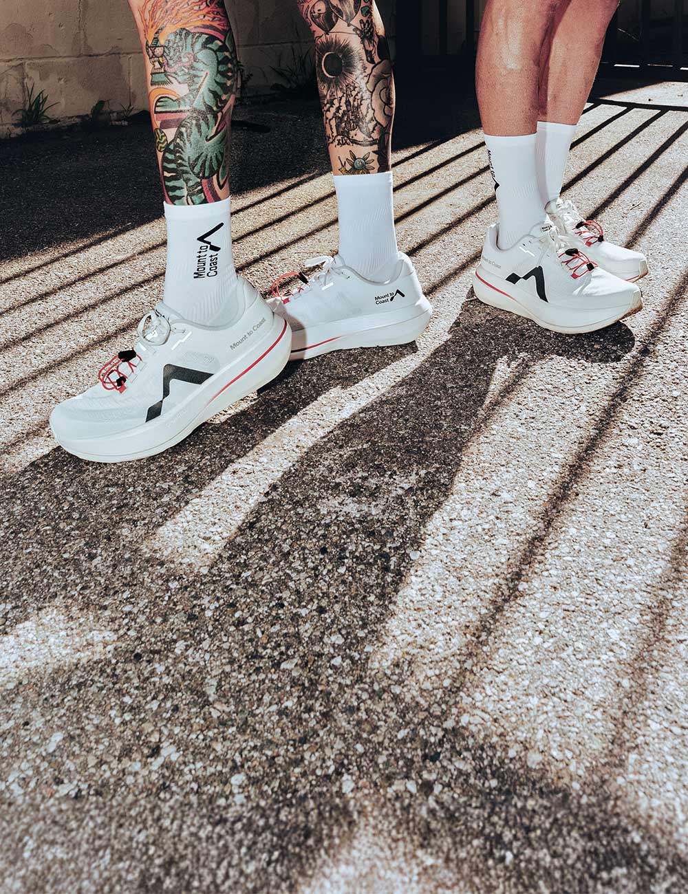 2 people wearing mount to coast c1 running shoes standing on pavement