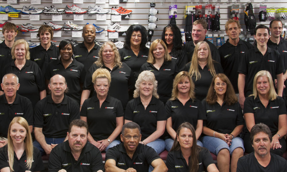 Group of Holabird Sports employees posing for a photograph, smiling in a coordinated and professional manner.