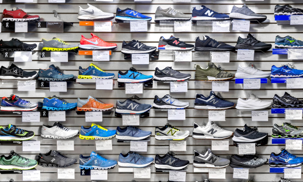 A display of athletic shoes showcasing a diverse collection of styles and colors, arranged neatly on a wall for customers to explore.