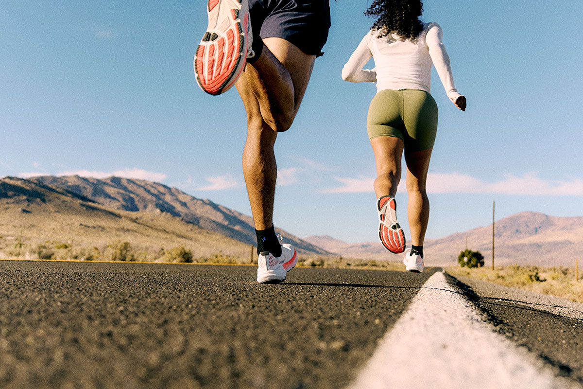 Two runners in Altra Experience Flow 3 shoes on a road with mountains in the background