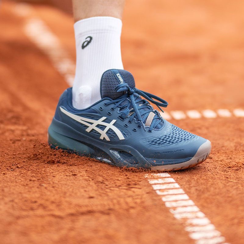 Men's ASICS tennis shoes in-use on a clay court
