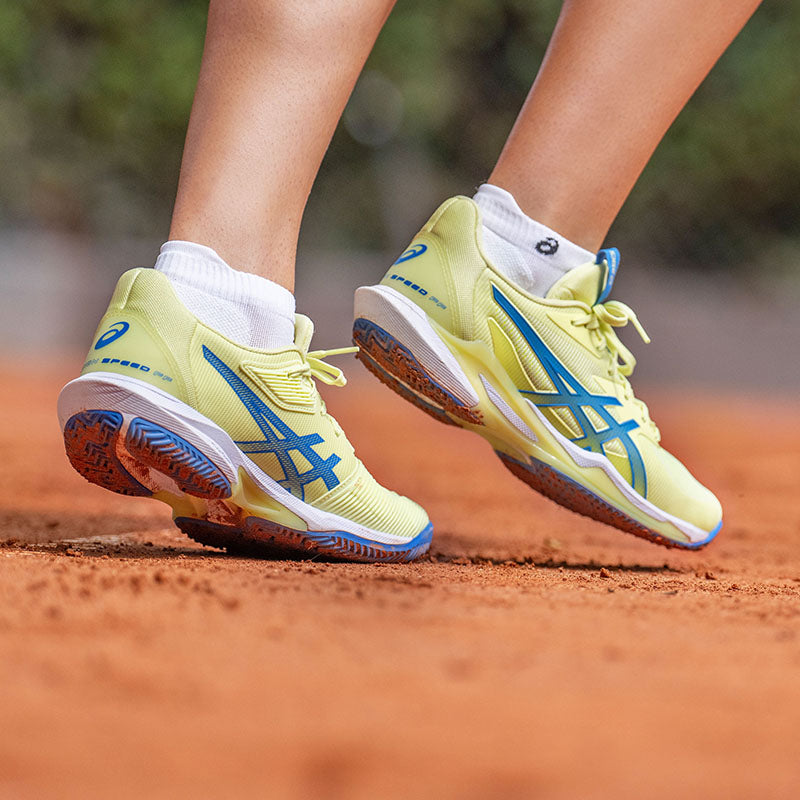 Women's ASICS tennis shoes in-use on a clay court