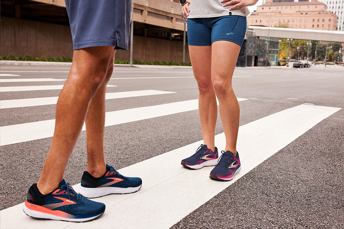 An image of a man and woman walking on a city street, both wearing the Brooks Ghost 16 shoes, known for their comfort and style suitable for urban environments.