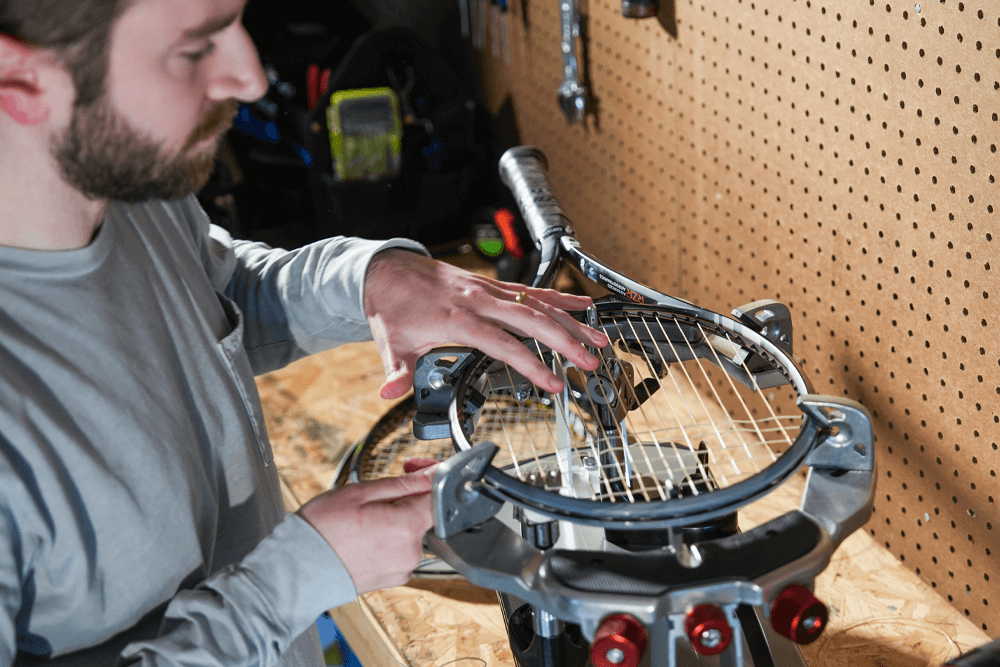 A man stringing his tennis racquet with a Gamma Momentum Stringing Machine.