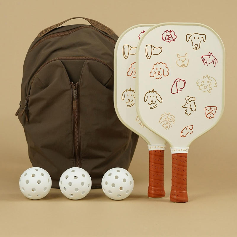 Recess Pickleball backpack and paddles on a tan background with 3 generic white pickleballs.