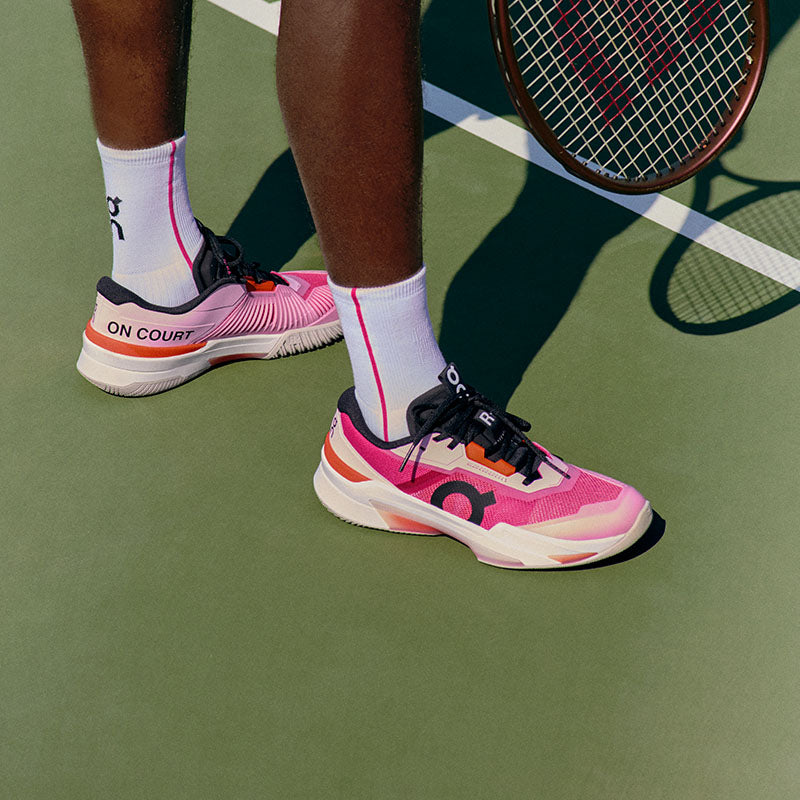 Person wearing pink and black On The Roger Pro Fire tennis shoes on a tennis court