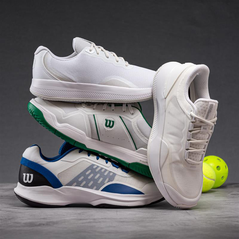 Stack of white tennis shoes with colorful accents on a gray surface, featuring a Wilson logo.