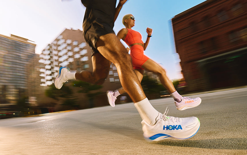 Man and woman running on road in HOKA Skyward X 2 running shoes.