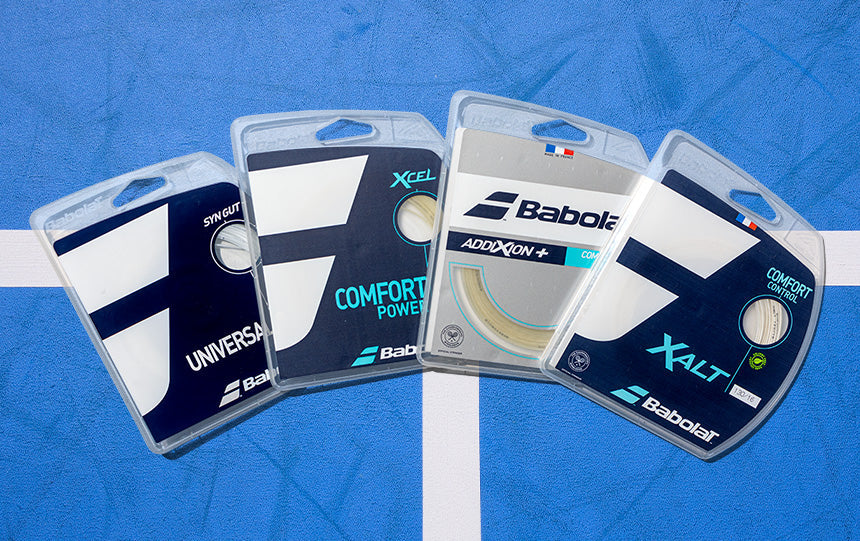 Four Babolat tennis string sets on a blue court surface