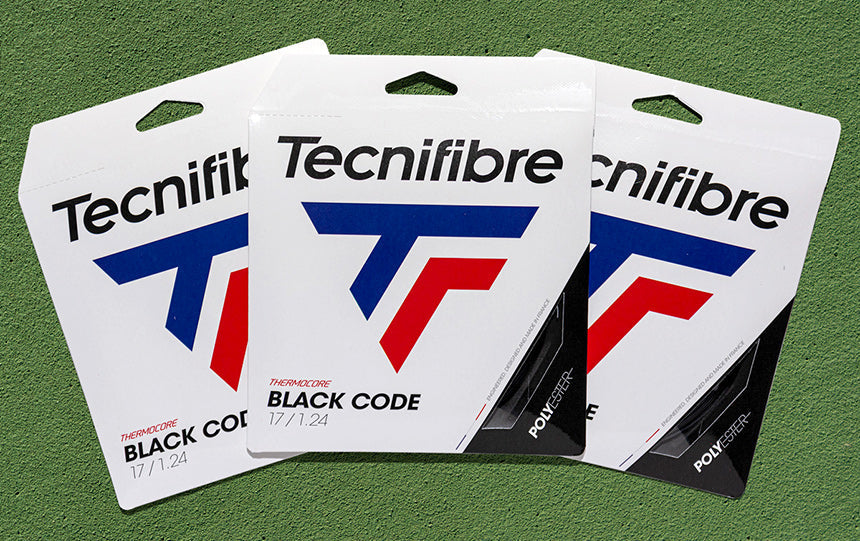 Three Tecnifibre Black Code string sets on a green court surface