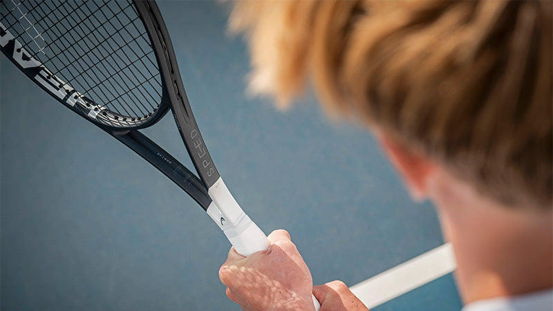 Over-the-shoulder view of a person holding a HEAD Speed 2026 tennis racquet on a blue court.