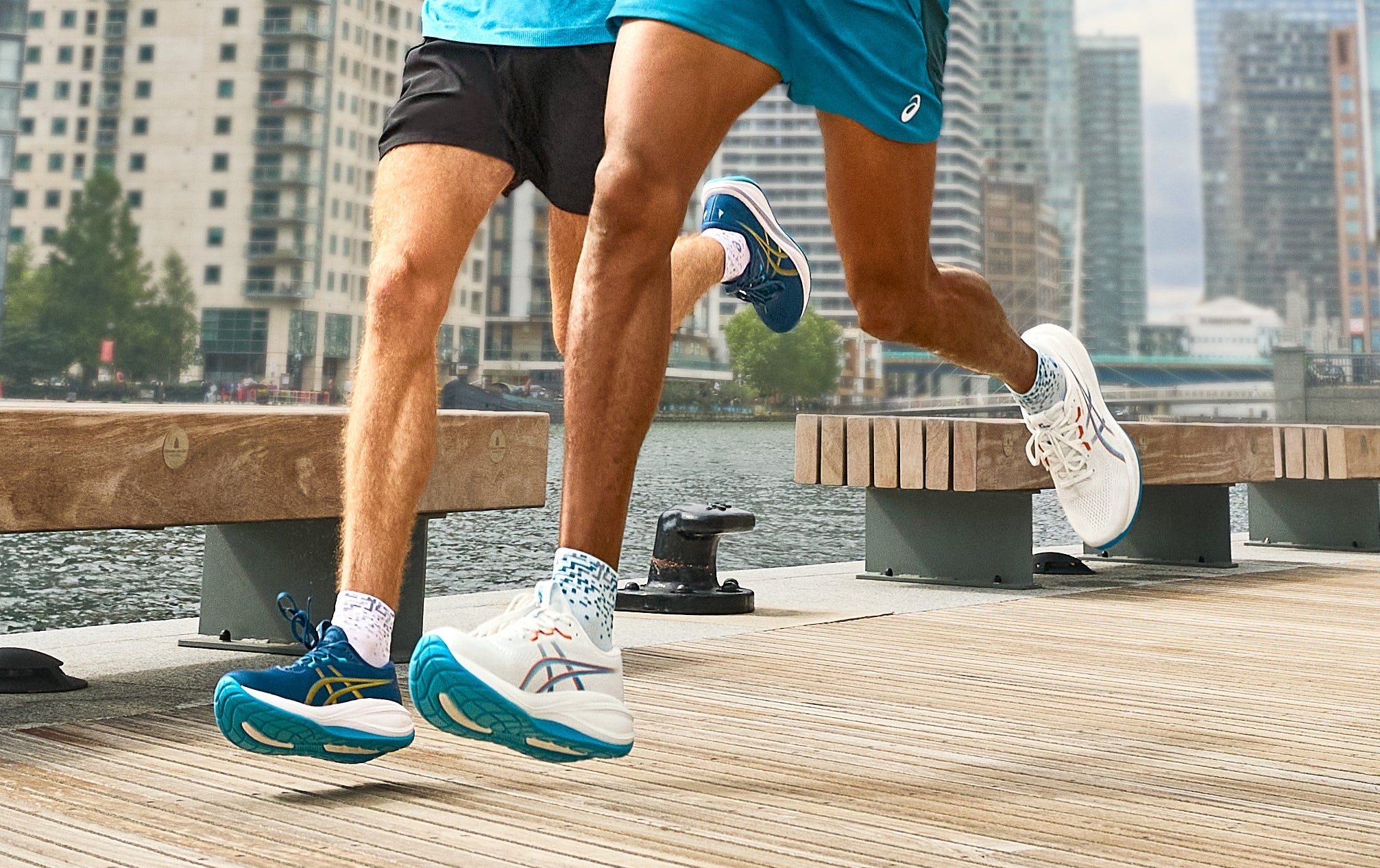 2 people running on a promenade along the water in asics running shoes.