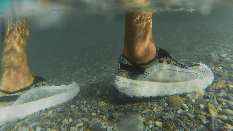 underwater image of a person wearing Salomon Solamphibian active water shoes in a shallow river