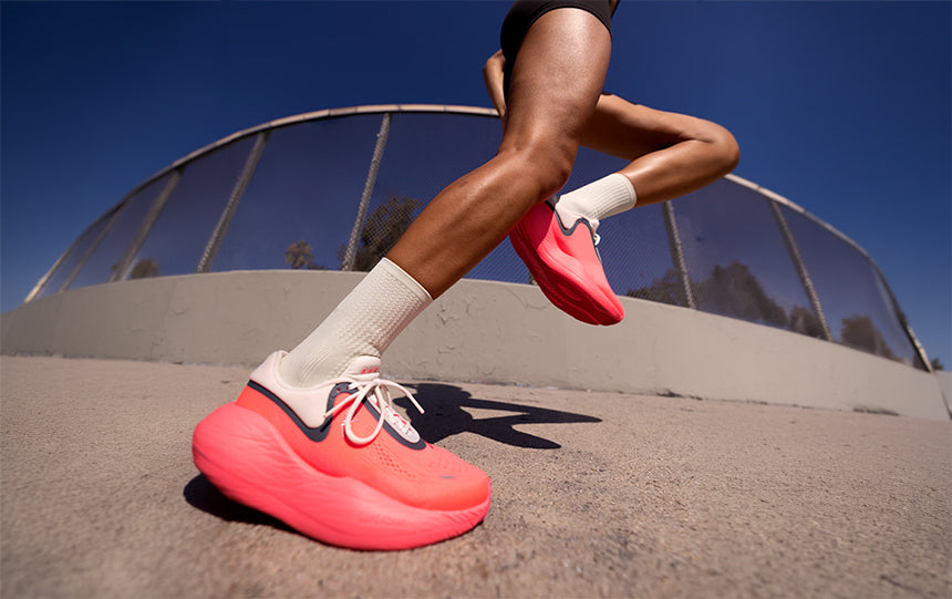 A person running on a sidewalk wearing pink and white R.A.D. UFO unisex running shoes