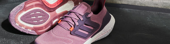 Upper and outsole closeup of a pair of adidas Ultraboost 22 Women's Magic Mauve/Legacy Purple/Turbo running shoes.