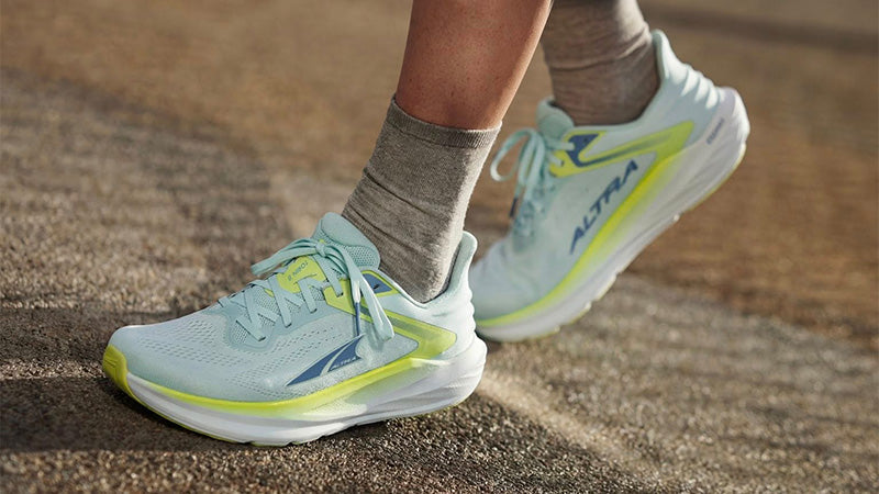 A person standing on a paved surface wearing light blue Altra Torin 8 women's pastel teal running shoes 
