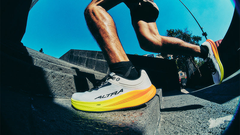 A person running up concrete stairs wearing Altra Torin 9 running shoes