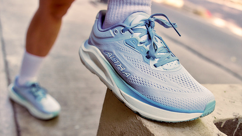 A person wearing women's Altra Torin ST running shoes stretching on a concrete structure