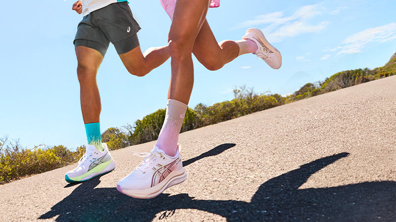 Two runners on a paved road in ASICS GEL-Kayano running shoes