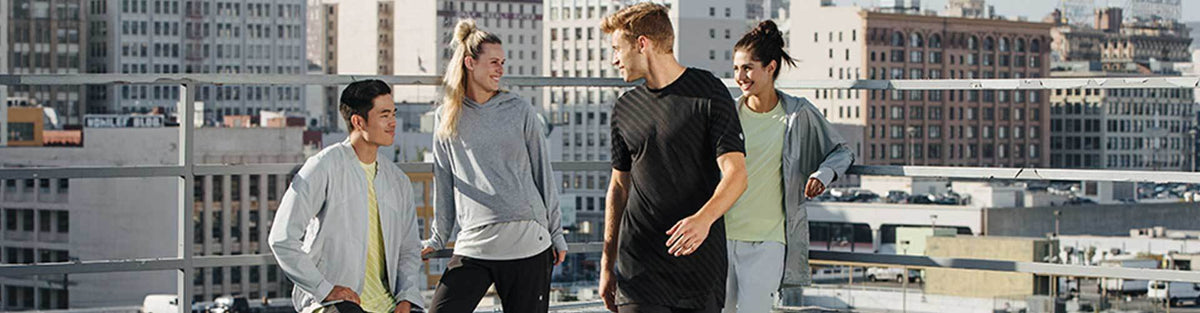 Group of people wearing ASICS athletic running apparel in front of city skyline