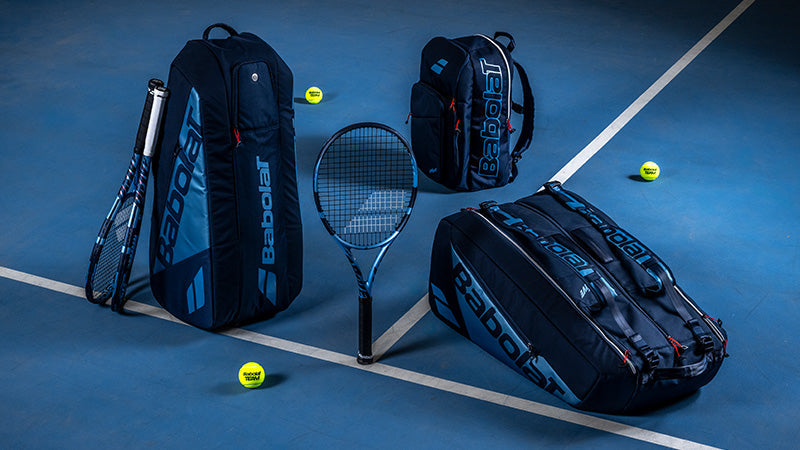 Babolat Pure Drive 2025 tennis racquets and bags on a blue court