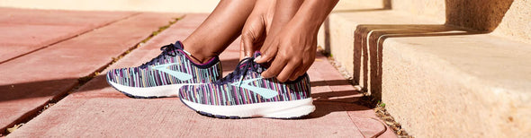 Woman tying laces of colorful Brooks running shoes
