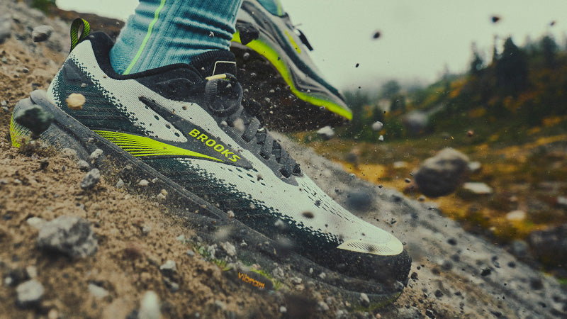 Close up of a trail runner in action on a rocky hillside wearing Brooks Cascadia 20 trail running shoes 