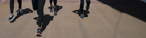 A group of people running down a sidewalk in Brooks Levitate Stealthfit 5 running shoes.