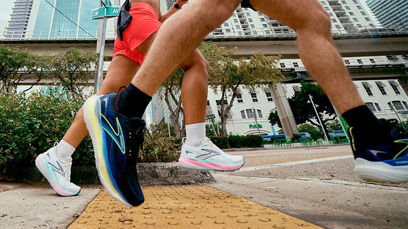 Two people running on a city sidewalk in Brooks Glycerin 22 and GTS 22 running shoes.