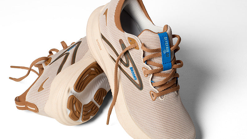 Closeup of a pair of tan Brooks Glycerin 22 running shoes with brown and blue accents on a white background