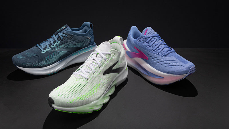 Three Brooks running shoes in different colors on a dark gray studio background.