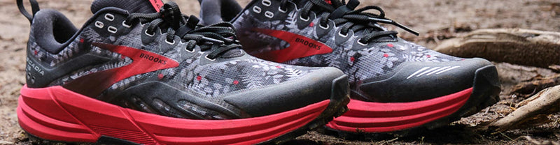 Close-up of black, gray and red Brooks Cascadia 16 Sasquatch trail running shoes.