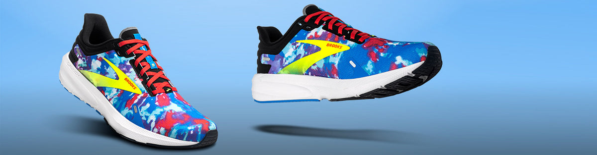 Pair of Brooks Launch 9 Tie Dye Edition running shoes on a blue gradient background.