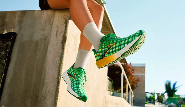 A Brooks Ghost 14 Run Lucky running shoe sitting on beads and a pot of gold in a festive St. Patrick's Day photo booth with balloons, confetti and streamers.