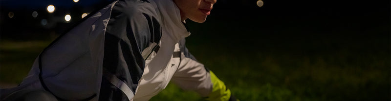 A person stretching in a Brooks Run Visible running jacket.