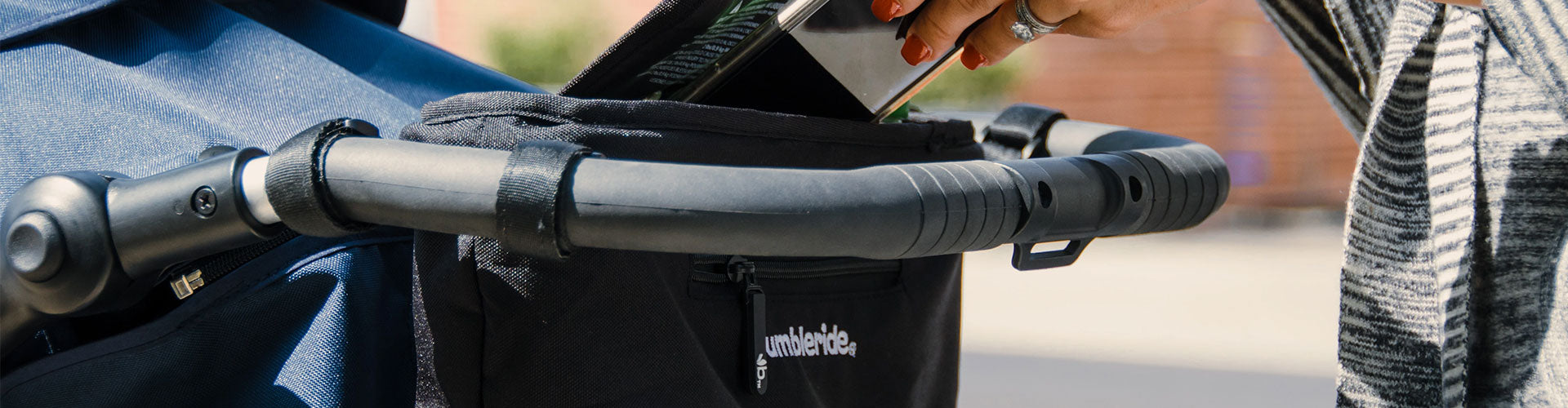 Woman putting phone into Bumbleride Parent Pack