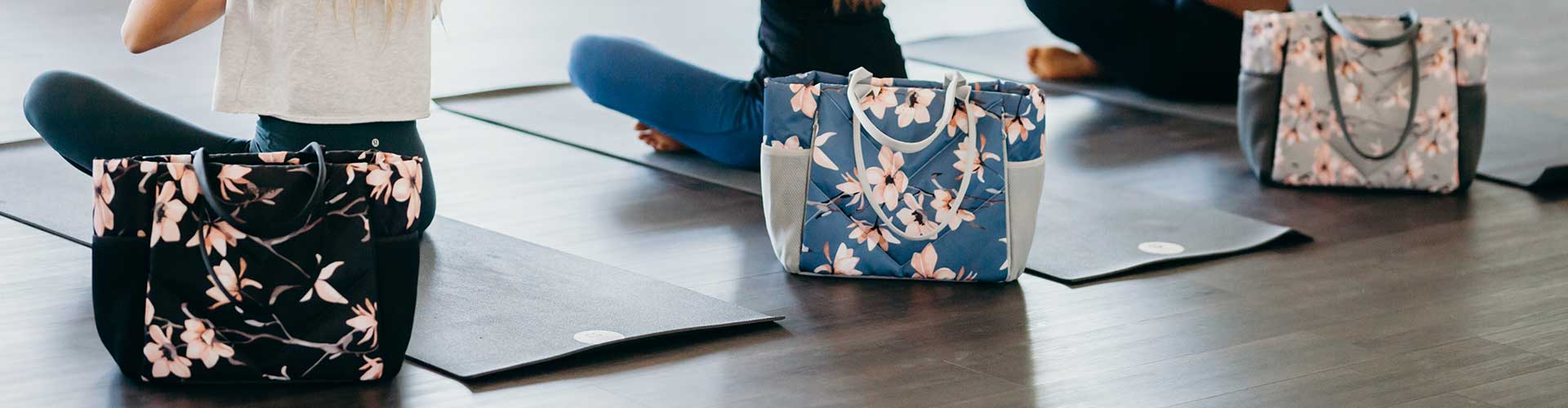 Woman in yoga class with black, blue, and gray cherry blossom Vooray totes