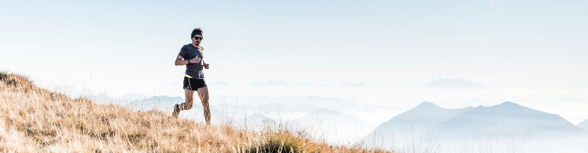 Man running on field in front of mountains
