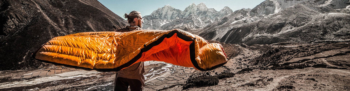 Man camping outdoors with orange sleeper bag