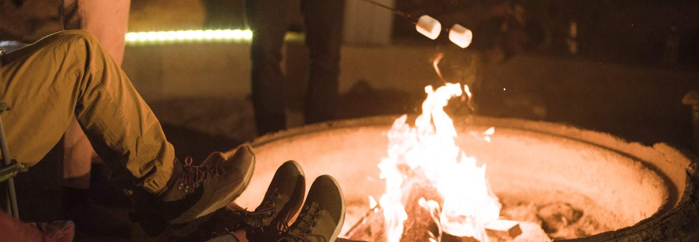 Group of people sitting near campfire roasting marshmallows