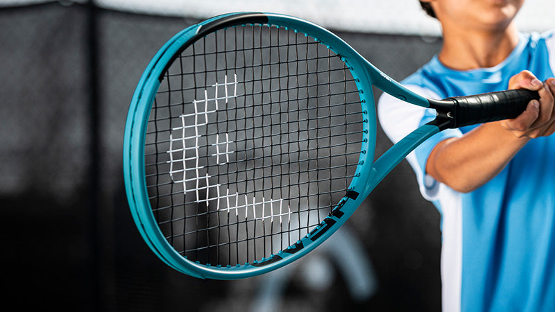 Closeup of a child swinging a blue HEAD Boom Junior 25 2026 tennis racquet