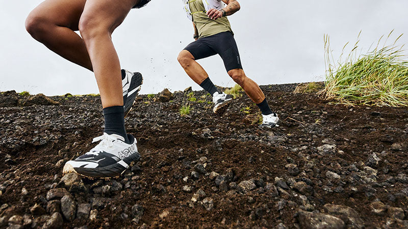 two people running on a rocky hillside in HOKA Speedgoat 7 trail running shoes