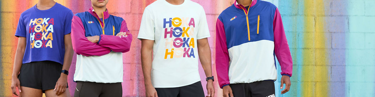 Men and women in front of colorful wall wearing HOKA Start Pack t shirt and jacket